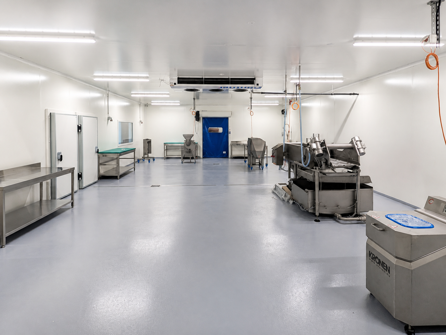 Atelier alimentaire avec tables de travail, machines et équipement frigorifique au plafond